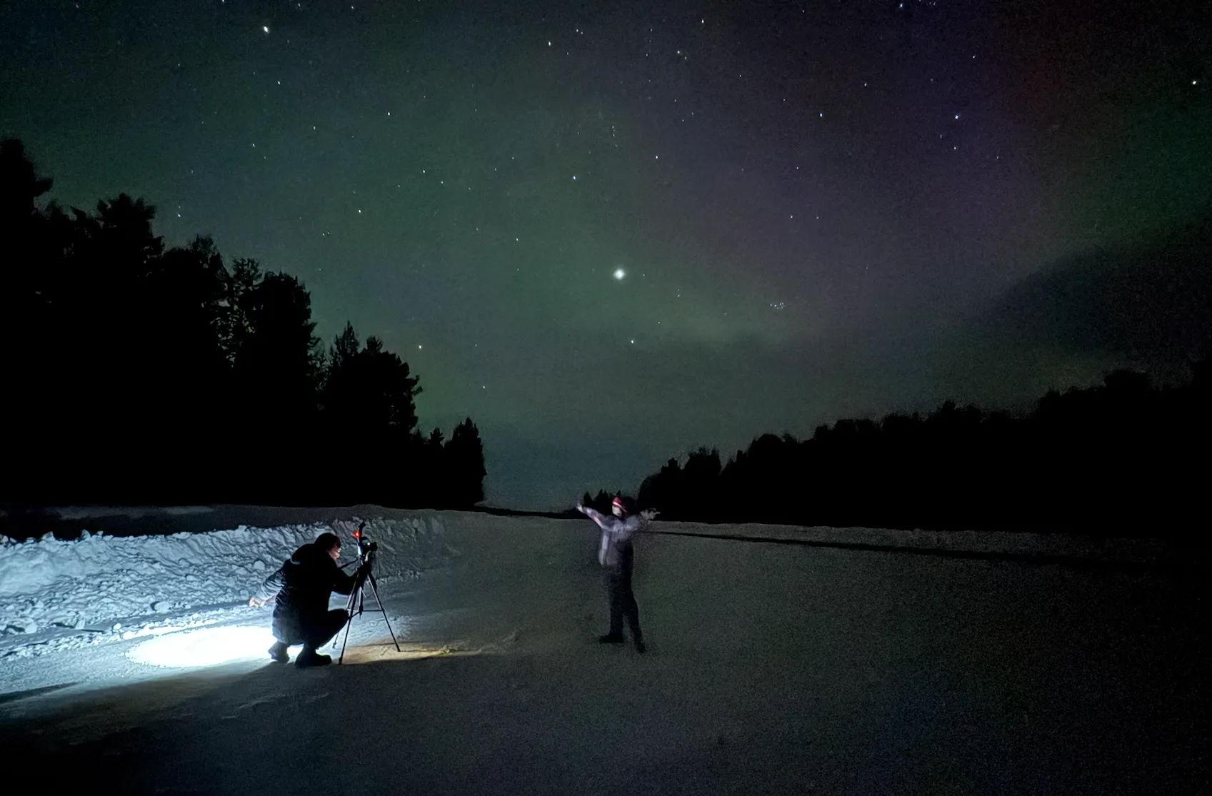 Aurora photography tour — guide helping with camera settings under the northern lights Murmansk